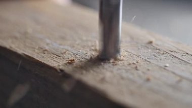 Tahtada delik açarken yakın mesafeden ateş edilmiş. Uçan odun parçaları ve toz. İç tasarım ve ev dekorasyonu için ahşap tasarım ve el yapımı sanat. diy marangozluk mobilyaları zanaatkar tarafından yapıldı