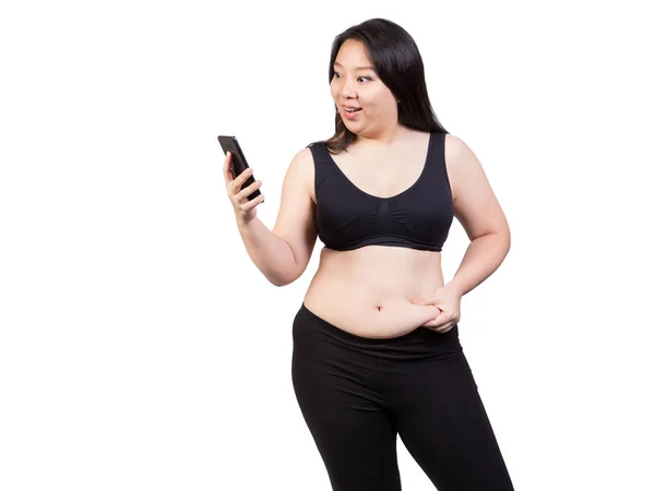 Mujer gorda exprimir la grasa del vientre mirando la cara del teléfono móvil sonrisa feliz concepto de pérdida de peso aislado sobre fondo blanco —  Fotos de Stock