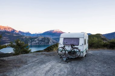 Fransız Alps Gölü Lac de Serre-Poncon yakınındaki bir görünüm ile bir dağın tepesinde bir bisiklet ile karavan park