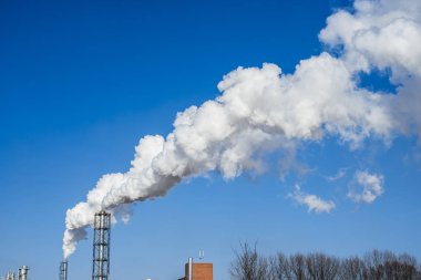 Çok duman mavi gökyüzü güneşli kış gününde, Letonya ile fabrika boru yakın çekim