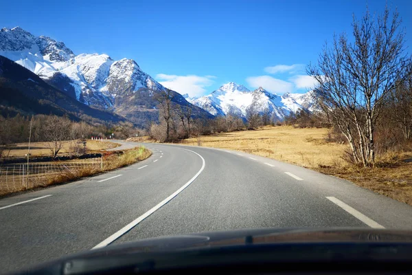 A view from the car on an asphalt road in French Alps mountains near Parc Ecrins on a clear day