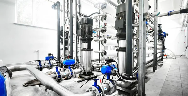 Büyük endüstriyel arıtma tesisi ve kazan dairesi. Parlak çelik metal borular ve mavi pupms ve vanalar.