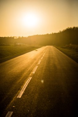 Gün batımında asfalt bir ülke yol ve alanları, saf altın ışık, Letonya