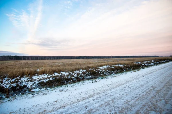 Smuts Snötäckt Landsväg Genom Fälten Vid Solnedgången Skogen Bakgrunden Lettland — Stockfoto