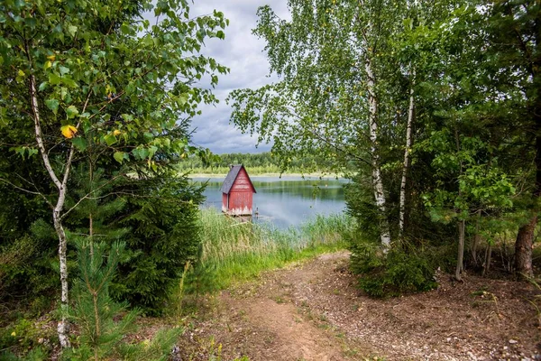 A small red wooden house near the lake and the forest, Latvia