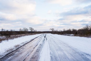 Gün batımında karla kaplı tarlalardan geçen kırsal yolun manzarası. Paldiski, Estonya