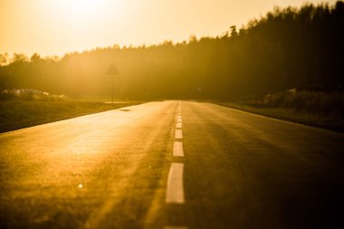 Gün batımında asfalt bir ülke yol ve alanları, saf altın ışık, Letonya