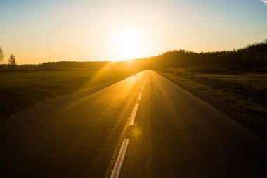 Gün batımında asfalt bir ülke yol ve alanları, saf altın ışık, Letonya
