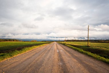 Ülke kir yol, alanlar ve ormanlar üzerinde renkli günbatımı bulutlar. Letonya