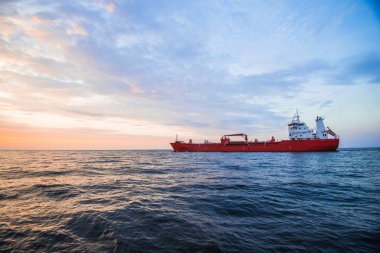 Baltık denizi ve arka planda kargo gemisi üzerinde renkli gün batımı, Letonya