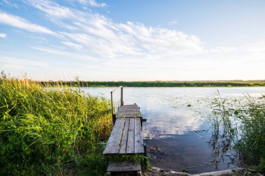 Gölün yanında küçük bir ahşap köprü. Yaz gün batımı, Letonya