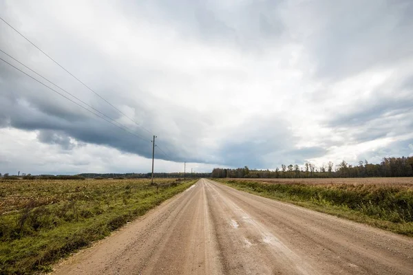화창한 농문화 필드를 비포장 폭풍우 하늘입니다 라트비아 — 스톡 사진