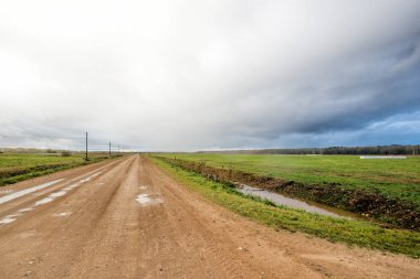 Ülke kir yol, alanlar ve ormanlar üzerinde renkli günbatımı bulutlar. Letonya