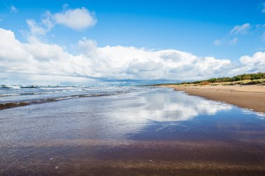 Berrak mavi gökyüzüne, dalgalara ve bulutlara karşı Baltık denizinin manzarası, Letonya