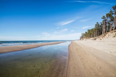 Güneşli bir günde bulutlu mavi gökyüzü altında Baltık deniz kıyısı ve deniz manzarası, Letonya