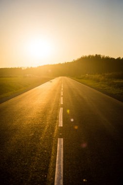 Gün batımında asfalt bir ülke yol ve alanları, saf altın ışık, Letonya
