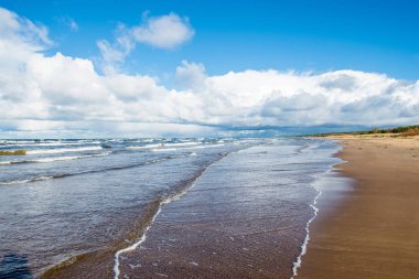 Berrak mavi gökyüzüne, dalgalara ve bulutlara karşı Baltık denizinin manzarası, Letonya