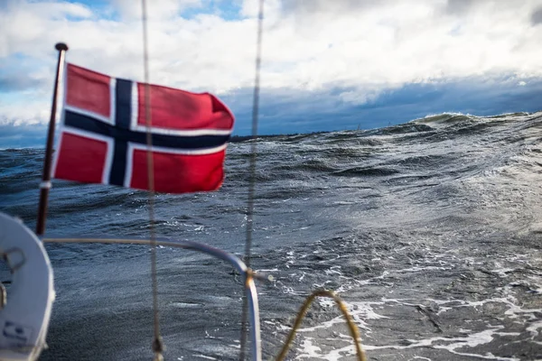 Winter sailing. A view from the yacht\'s deck to the bow. Norway flag close-up. Baltic sea, Latvia