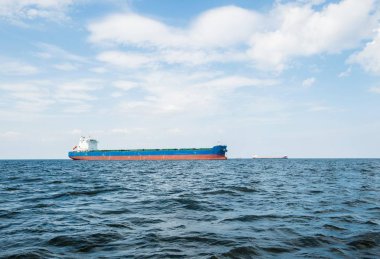 Bulutlu mavi gökyüzünün altında kargo gemisi, Baltık denizi, Letonya