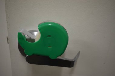 Yeşil scotch bant büyük beyaz kapı için endüstriyel kapı kolu üzerinde dinlenme.