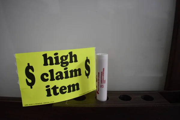 Yellow high claim item sticker next to white board and red dry erase marker.