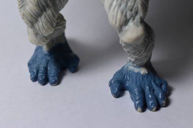 Beyaz zemin ve arka plan ile oyuncak beyaz goril closeup Mavi ayak.