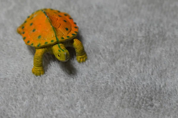 Beyaz bez yüzeyinde sarı kaplumbağa oyuncak closeup görünümü.