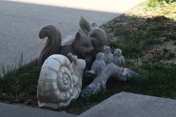 兔子和三只鸟的雕像躺在车道旁边的草坪上 — 图库照片