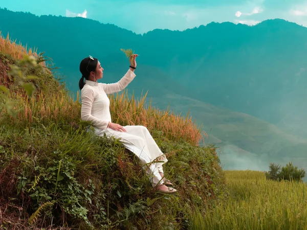 Woman in vietnamese traditional clothing at rice field