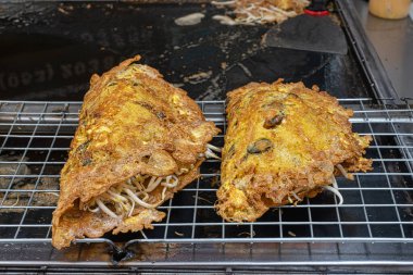 Izgarada iki porsiyon kızarmış midye krepi. Tayland sokak yemekleri ve tipik yemekler. Tayland yemeği konsepti, yemek konsepti. Ana malzemeler un, yumurta, midye ve fasulye filizleridir..
