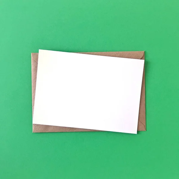 绿色背景上带信封的空白明信片 — 图库照片
