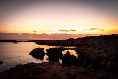Gün batımı arkaplanındaki kayalık kıyı şeridi görüntüsü 