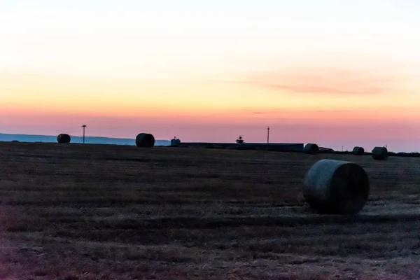 Salida del sol sobre un campo de trigo con fardos — Foto de Stock