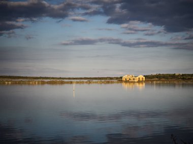 İtalya, Sicilya 'nın güneyinde doğal bir rezerv olan Vendicari' de yıkılmış bir binanın çekimi. Bina suya yansıyor.
