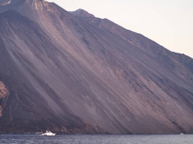 Yanardağın eteğinin denize düşmesi, yakınlarda tekneler.