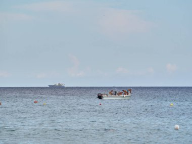 San Lorenzo, Syracuse - 24 Ağustos 2018: Yaz güneşli bir günde Syracuse yakınlarındaki güzel tropikal San Lorenzo plaj Shot. İnsanlar sahilde tekneyle dolaşıyor, eğleniyor ve dinleniyor.