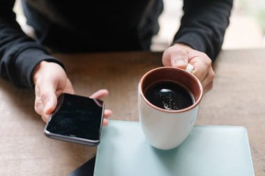 Bir fincan kahveyle bir erkeğin elleri.