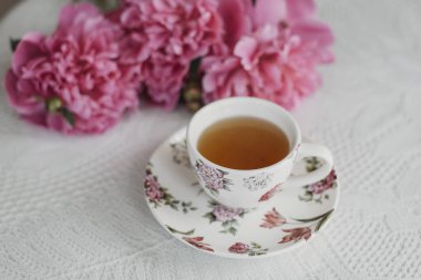 Masada pembe şakayıklar ve bir fincan çay.