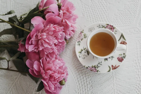 Masada pembe şakayıklar ve bir fincan çay.