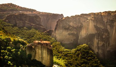 Meteora Yunanistan Manastırı. Göz kamaştırıcı panoramik manzara. Bulutlu destansı mavi gökyüzüne karşı dağlar ve yeşil orman manzarası. Unesco miras nesnesi.