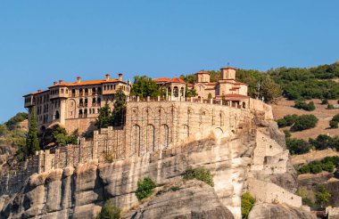 Meteora Yunanistan Manastırı. Göz kamaştırıcı panoramik manzara. Bulutlu destansı mavi gökyüzüne karşı dağlar ve yeşil orman manzarası. Unesco miras nesnesi.