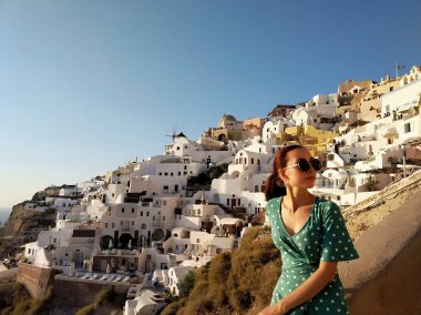 Oia renkli turuncu günbatımı izlerken güzel genç kadın, Santorini, Yunanistan