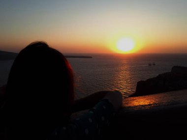 Oia renkli turuncu günbatımı izlerken güzel kadın, Santorini, Yunanistan