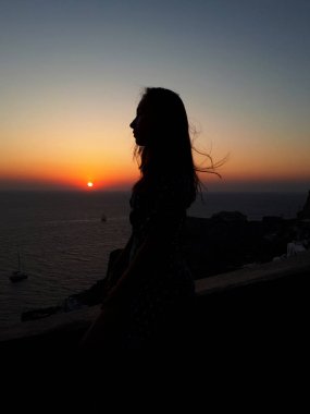 Oia renkli turuncu günbatımı izlerken güzel kadın, Santorini, Yunanistan