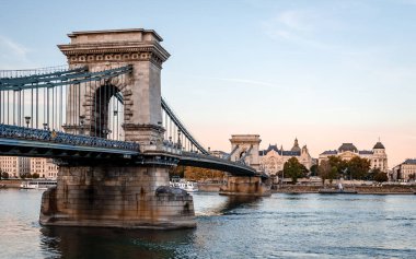 Budapeşte / Macaristan - 4 Ekim 2018: Alacakaranlıktaki Zincir Köprüsü manzarası. Tuna Nehri boyunca uzanan asma bir köprü. Pest, Budapeşte 'nin doğu yakası, arka planda.,