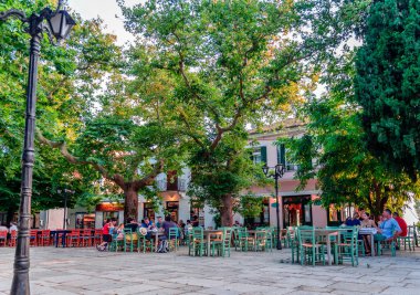 Lafkos / Yunanistan - 4 Temmuz 2020: Köyün tarihi meydanının manzarası, kafeteryalar ve restoranlar ve çok sayıda uçak ağacı.