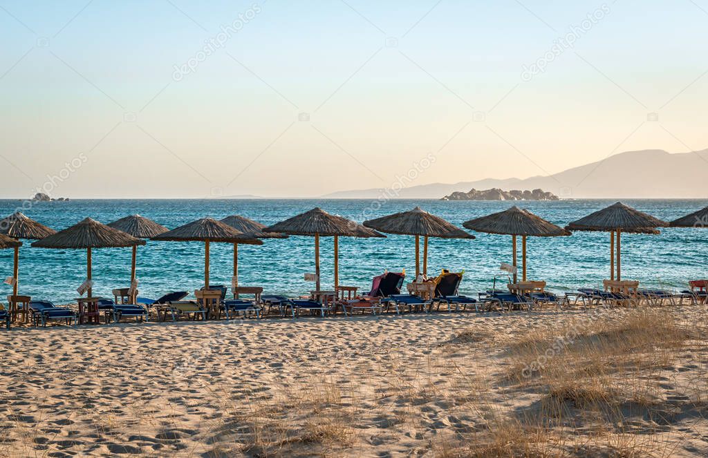 View of Plaka beach, with sunbeds and umbrellas, in the afternoon. Naxos island, Greece