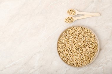 Tabakta iki kaşıkla çam fıstığı. Üst görünüm bej mermer tablo üzerinde kopya alanı ile.