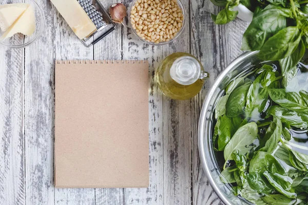 Malzemelerle geleneksel sos pesto tarifi için Mockup: peynir, fındık, zeytinyağı, fesleğen, ahşap beyaz arka plan üzerinde sarımsak.