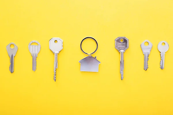 Sleutels en Trinket in vorm van huis in het midden op kleur achtergrond, Top View. — Stockfoto